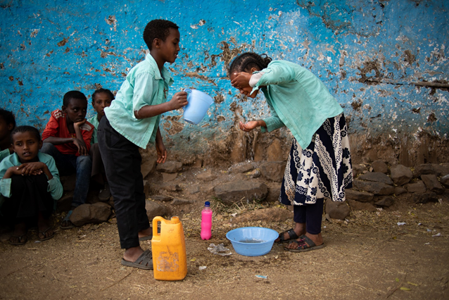 Two children in Gondar Zone, Amhara Region, Ethiopia, wash their faces as part of community-driven trachoma control practices